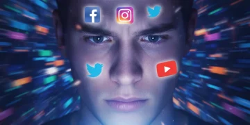 Persona con rostro iluminado por pantalla de smartphone, rodeada de iconos de redes sociales.
